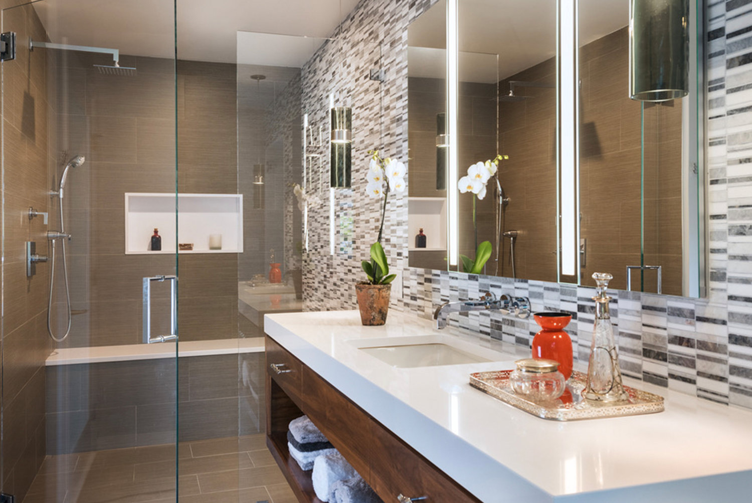 A calming palette of white counter tops, gray and white mosaic stone and glass, and mocha porcelain floors, keeps the single-windowed bathroom light and bright.