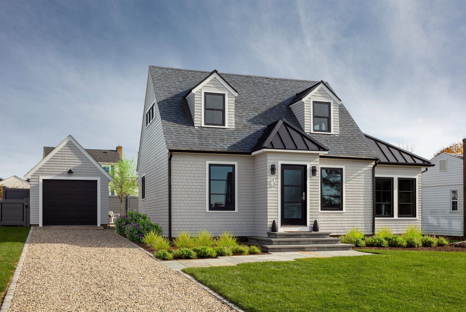 Both inside and out, a prescribed use of black elements frame neutral colors adding interest and sophistication to the humble  Cape Cod style home.