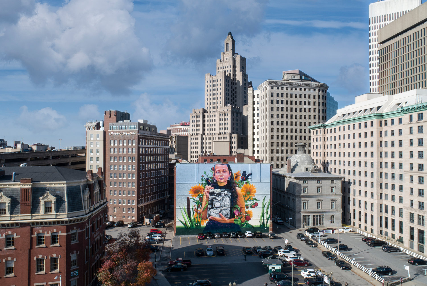 The “Still Here” mural by Gaia stands out against the city skyline