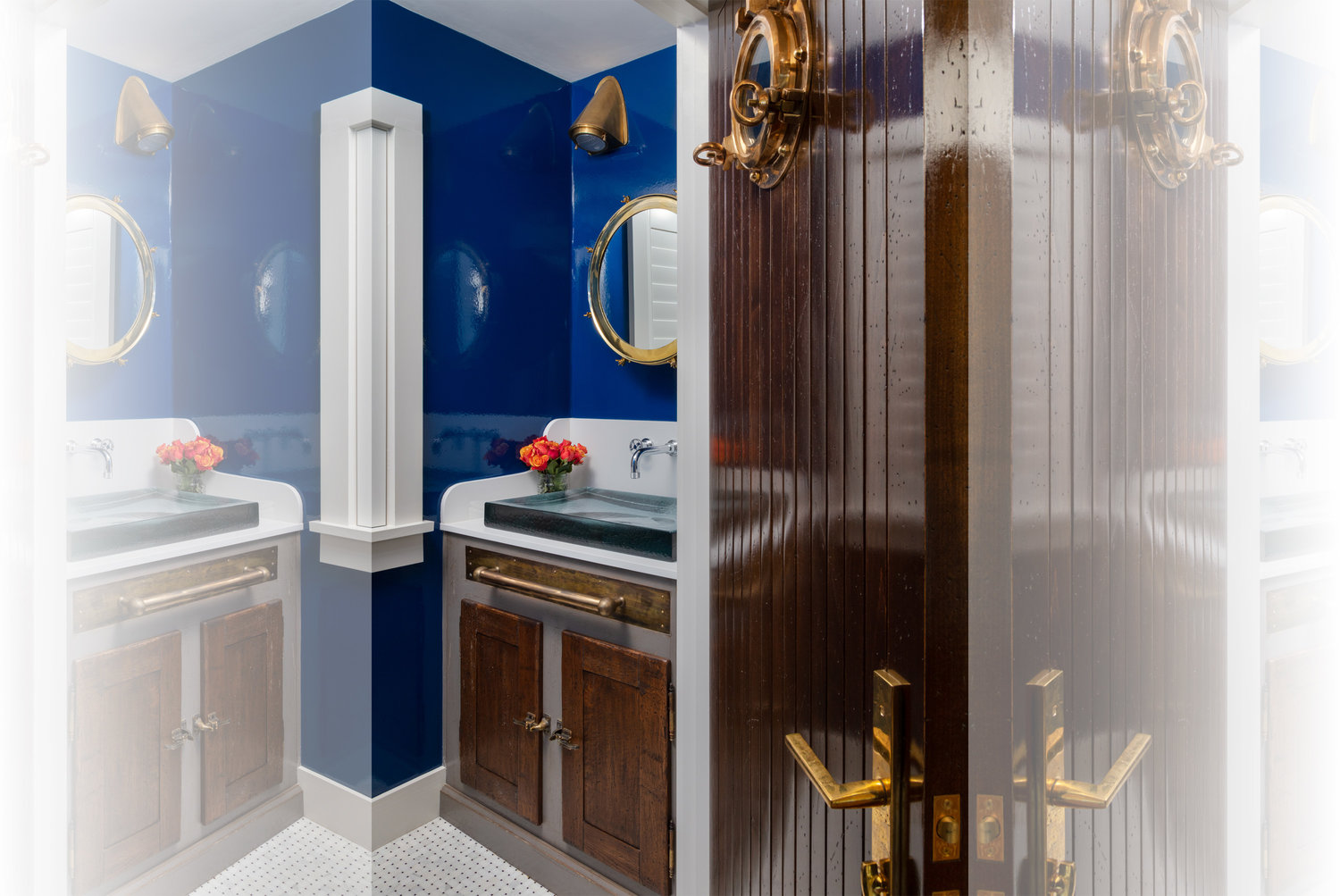 A vintage trunk was retrofitted to become a sink base with a modern blue sea glass Kohler sink atop; vinyl gloss blue wallcovering adds a dimension reminiscent of a fiberglass interior of a ship