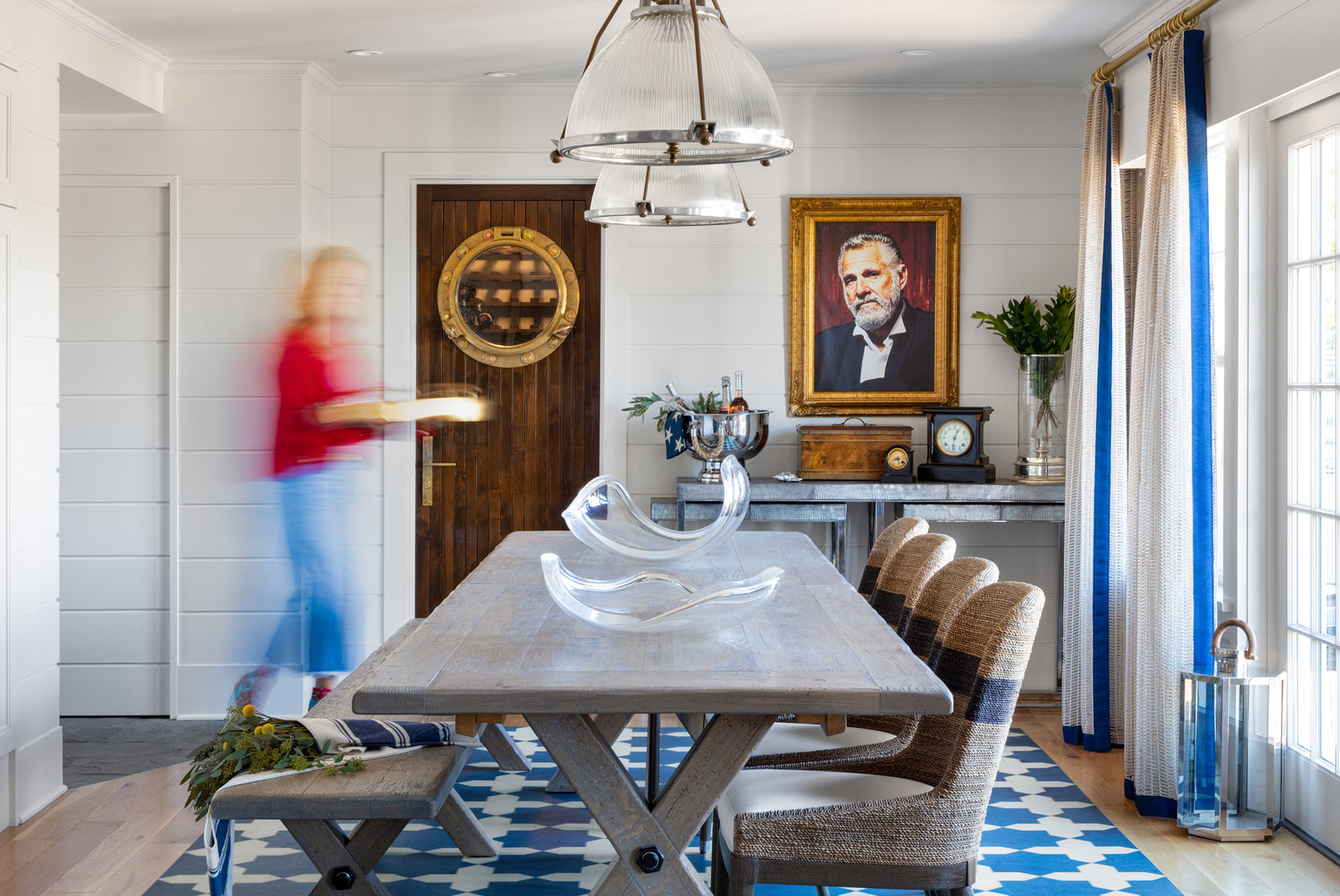 An antique ship lantern hangs above the custom wide plank dining table and bench ready to serve up to 16; an easy-care vinyl floorcloth adds fuss-free flair. The porthole door hides a walk-in wine cellar and veggie storage unit.