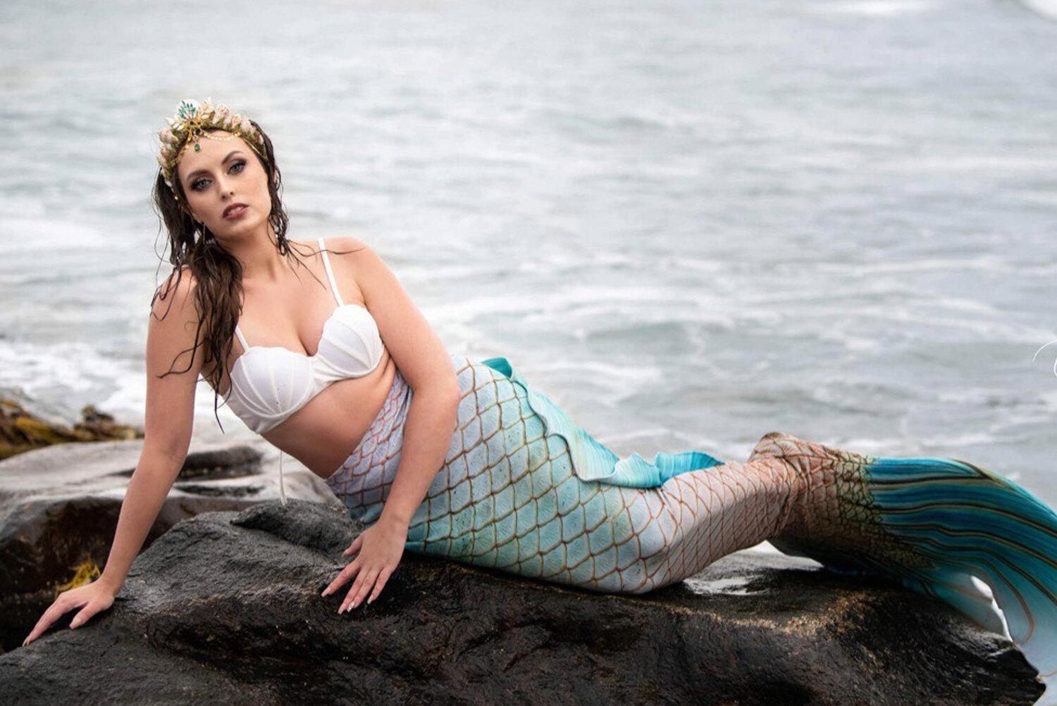 Mermaid Alyssa Wick sunbathing on the rocky coastline